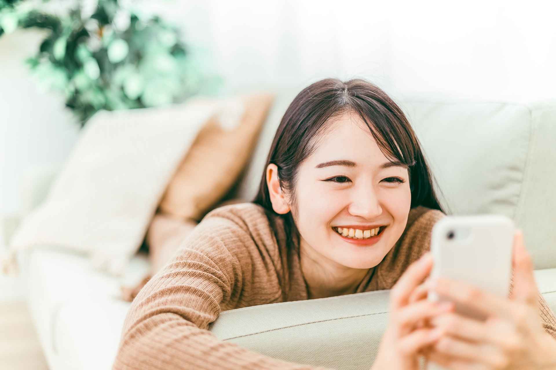 寝ころびながらスマホを操作する女性